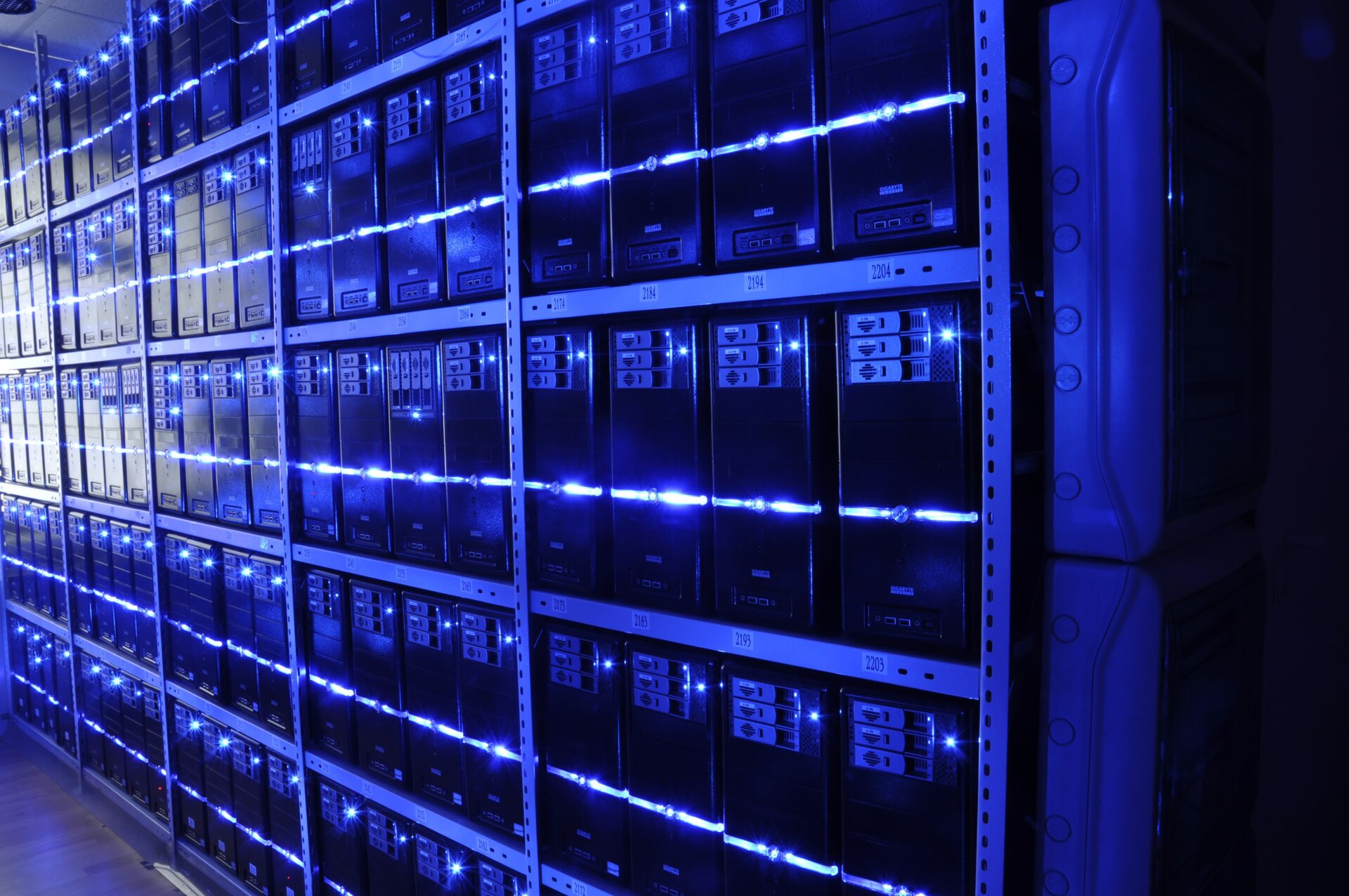 Corredor de um data center com fileiras de servidores iluminados em azul