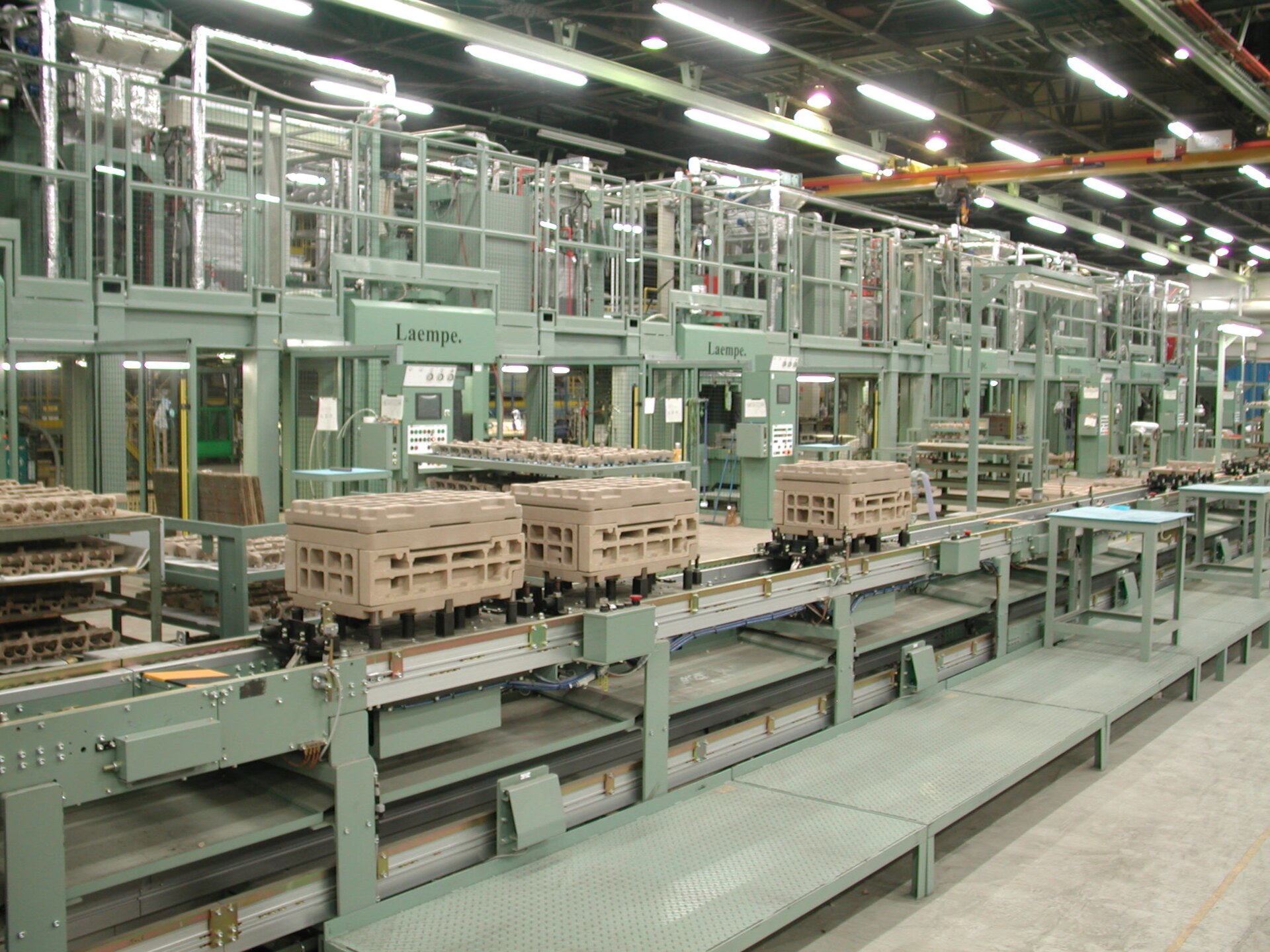 Linha de produção industrial com esteiras e estações de montagem enfileiradas