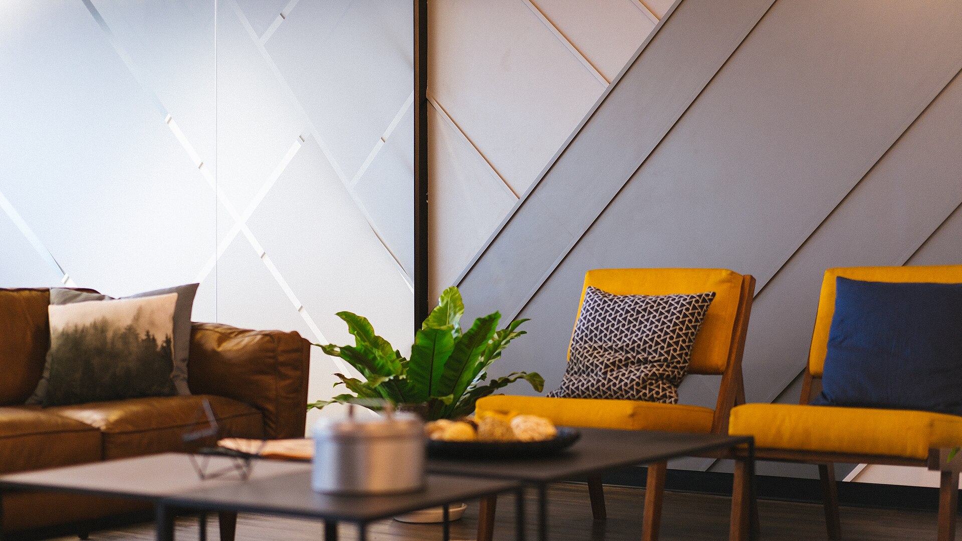 Sala de reunião informal com poltronas amarelas, sofá de couro e mesa de centro